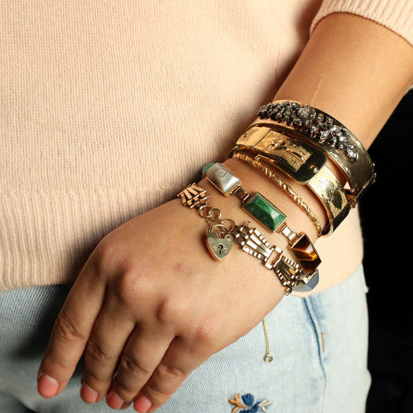 Hand wearing multiple bracelets with a dark background