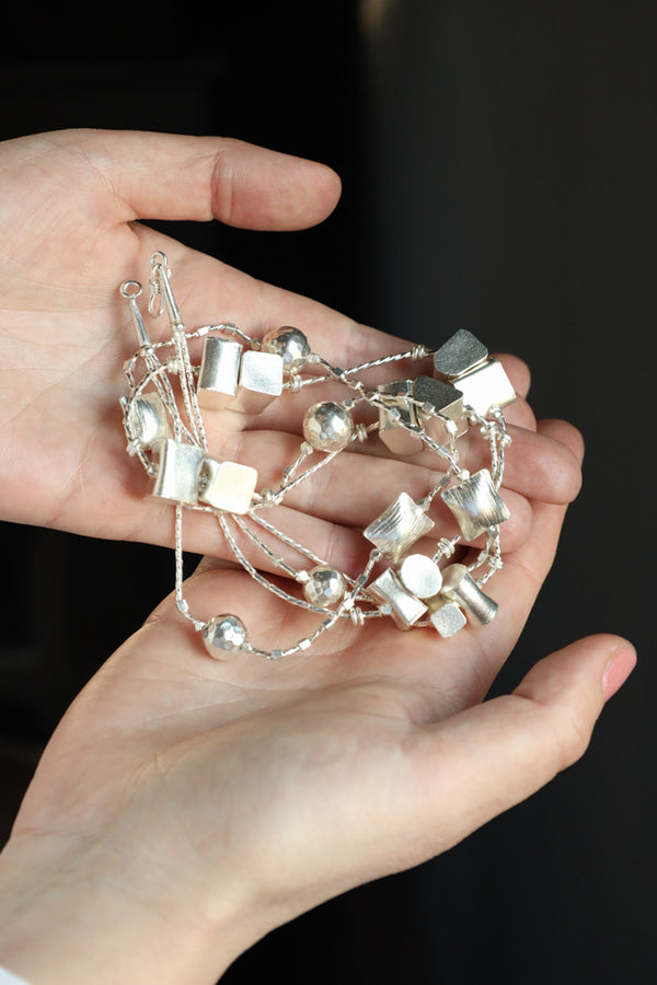 A high quality funky silver satellite necklace made of solid 925 sterling silver. Handmade by our workshop, this liquid silver two-strand pebble chain is made of 'satin' mildly brushed silver beads. The beads have mixed geometric shapes and are gracefully spaced alonside the two strands.

The necklace 55 cm long and is a beautiful day-to-night piece. truly an outstanding and fun piece of jewelry which will add a little spice to any look. 

Details:
Metal: 925 brushed (satin look) sterling silver, hallmarked