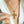Gold cross necklace with green gemstones worn by a person, close-up on a white background.