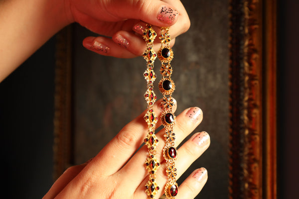 Close-up of hands holding a necklace with a dark background