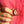 Hand holding a crescent moon brooch with red stones against a pink background