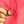 Hand holding a crescent moon brooch with red stones against a pink background