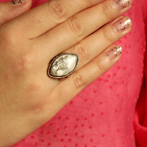 Hand wearing a large ring with a clear stone against a pink background