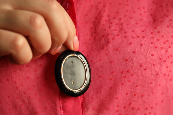 Hand holding a small round object against a red textured background