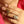 Close-up of a hand wearing gold rings with a pink shirt background