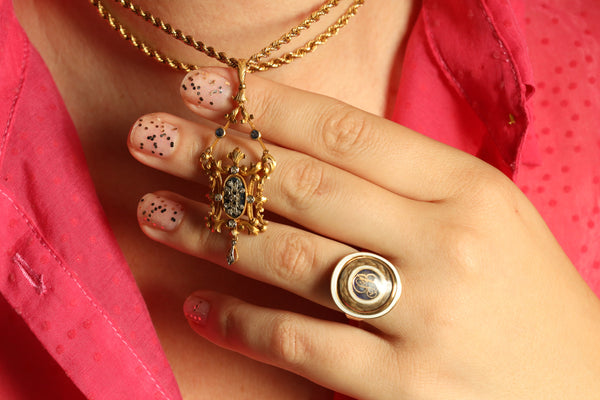 Close-up of a hand wearing gold rings with a pink shirt background