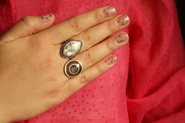 Hand wearing two rings with a red fabric background