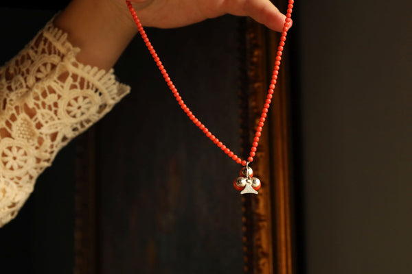 Red beaded necklace with a star pendant held by a person wearing a lace sleeve.