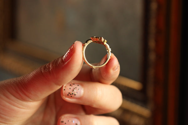 Gold ring held between fingers with a blurred background