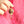 Gold key-shaped pendant held by a hand against a pink background