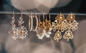 Collection of gold and silver earrings on a rod against a blurred background