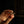 Hand holding a small gold cross against a dark background