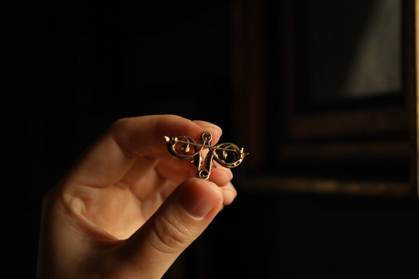 Hand holding a small gold cross against a dark background