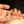 Two pearl earrings held between fingers against a dark background