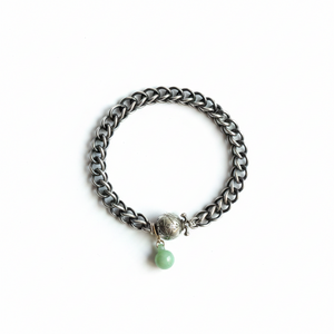 Silver chain bracelet with a green bead on a white background