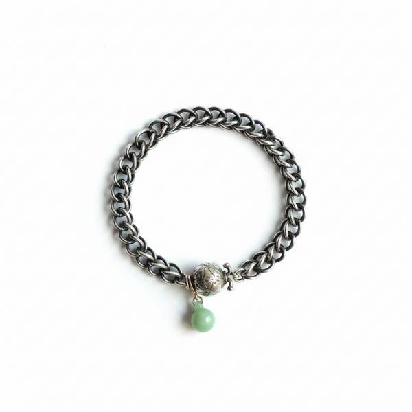 Silver chain bracelet with a green bead on a white background