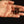 Pair of earrings held in a hand against a dark background