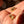 Gold earrings with gemstones held in a hand against a blurred background