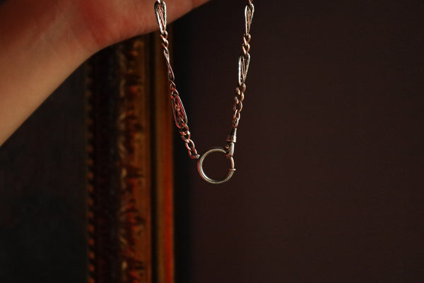 Close-up of a delicate chain with a small ring pendant on a dark background