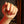 Close-up of a hand with painted nails holding a small object against a blurred background