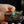Decorative object with a gold bird design and turquoise stone held by a hand against a blurred background