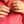 Close-up of hands holding a gold chain with a pink shirt background