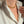 A close-up of a person wearing a delicate gold chain necklace, with their white shirt open to display the jewelry.