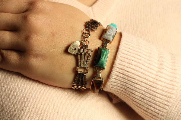 Close-up of a hand wearing a decorative bracelet on a beige background