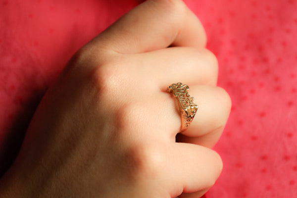 Gold ring on a person's finger against a red background