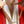 Gold chain necklace held by a person against a red background