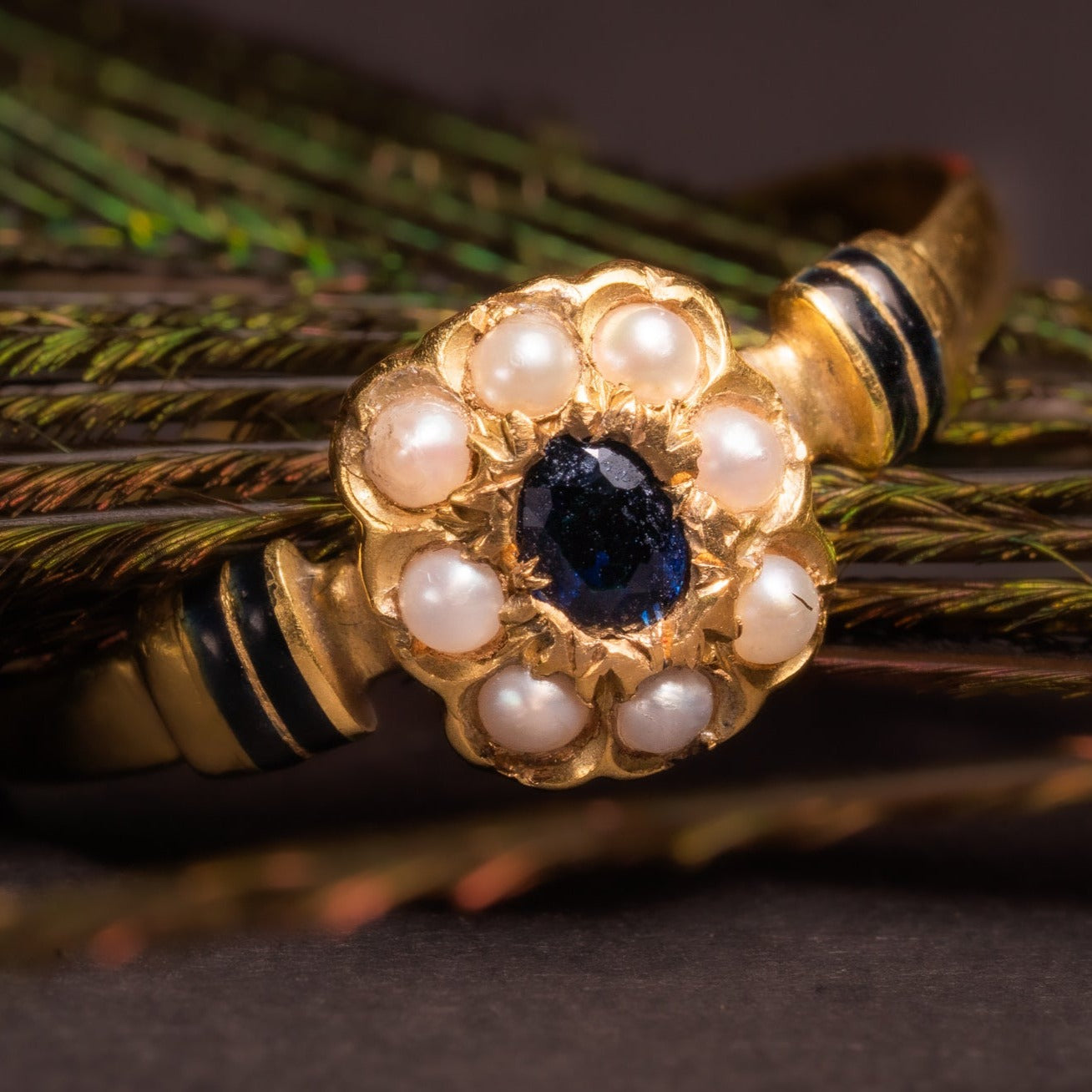 Such a striking and feminine sapphire gold ring! This marvelous antique Victorian ring is made of solid 18ct yellow gold.  The crown carries a natural sapphire, pearls and is accented with black enamel. Current size 7.75 - adjustable.