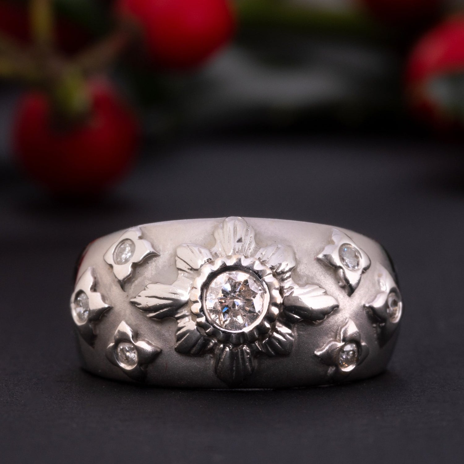 A white gold diamond starburst ring made of solid 18 ct gold and set with 0.35 ct worth of diamonds.  The shank of this celestial ring is rather wide and puffy, the front part is brushed and has a velvet-like gold texture. The celestial centerpiece is set with 7 diamonds.  The central diamond of 0.2 ct is set in an elevated 'star' setting and is surrounded by six smaller stones.